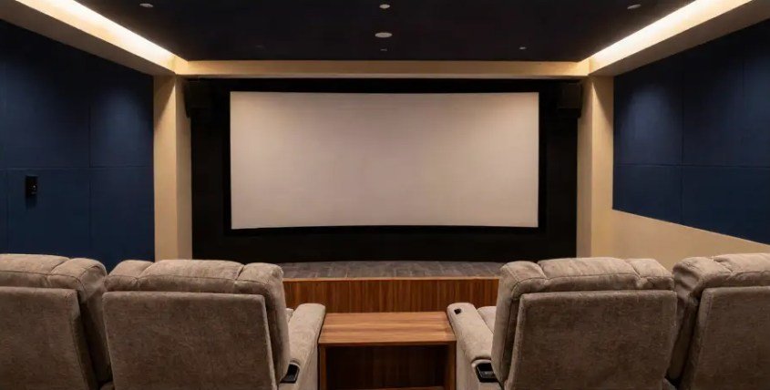 Home theatre with navy acoustic panelling, cove lighting and tiered recliners